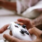 Close-up of hands holding a game controller with thumbs on the analog sticks
