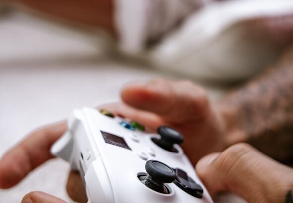 Close-up of hands holding a game controller with thumbs on the analog sticks