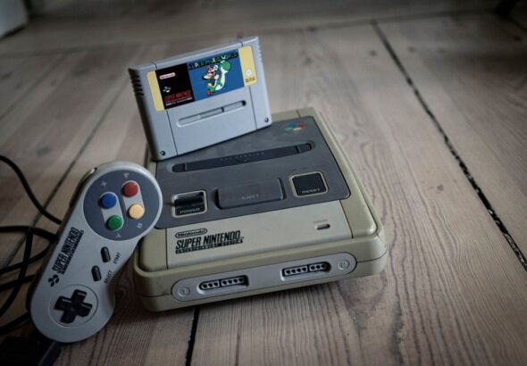 Vintage Super Nintendo style retro console and controller on wooden floor
