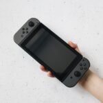 A hand holding a Nintendo Switch style handheld console