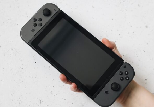 A hand holding a Nintendo Switch style handheld console